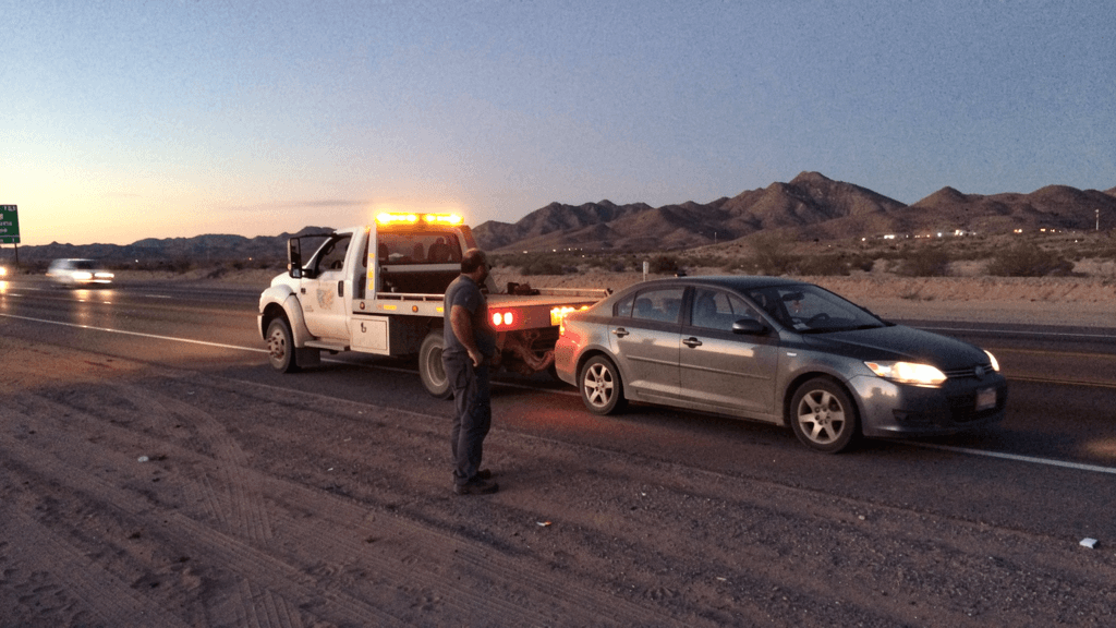 Tow truck helping a driver on an El Paso roadside at dusk